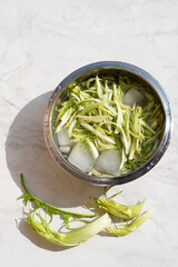 Puntarelle alla romana or asparagus Catalonian chicory salad in a bowl with ice and cold water to remove bitter taste. Roman cuisine. Italian traditional seasoning recepies:spring. Top view, sun light