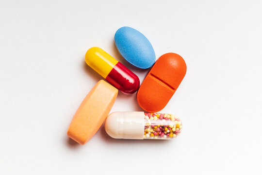 Close up picture of Coloured capsules , pills and tablets against a white background.