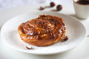 Bun with caramel and nuts in a plate on the table