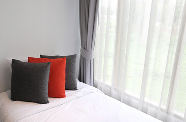 Pillows on bed near window with gray curtain