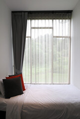 Pillows on bed near window with gray curtain