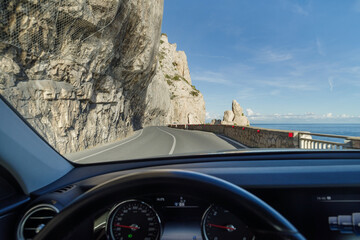 Driving on a coastal road winding along a cliff - 769842470