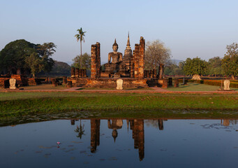 Sukhothai. Old buddhist temple ruins. Sitting Buddha statue nad pagoda reflecting in the pond....