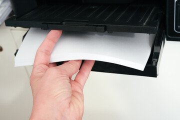 The woman inserts paper into the printer, home office, home office supplies, document printing,...