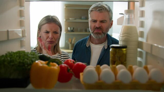 Adult middle-aged family couple woman man mature husband wife POV point of view from inside fridge open refrigerator feeling bad smell disgusting unpleasant spoiled rotten food meal awful stink odor