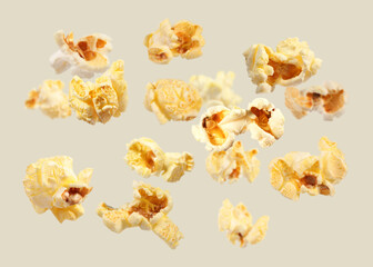 Tasty fresh popcorn flying on light grey background