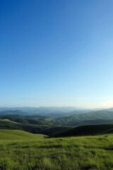 Fototapeta na wymiar Verdant hills roll under a clear sky, their curves casting soft shadows in the gentle light.