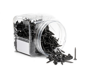 a tipped over open container of black drywall screws with screws spilled out isolated on white