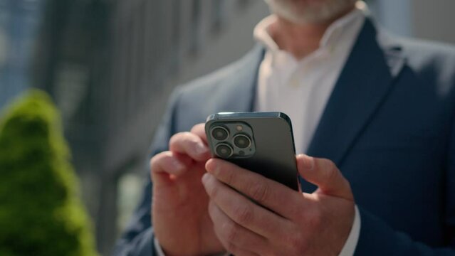 Moving shot Caucasian senior man using mobile phone looking away thinking happy smiling mature business entrepreneur middle-aged old businessman in city browsing smartphone chatting online outdoors