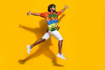 Fototapeta na wymiar Full size photo of good mood man dressed print shirt flying open palms look at logo empty space isolated on yellow color background