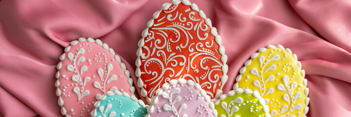 background banner greeting card for Happy Easter with colorful eggs gingerbread cookies on pink silk fabric background