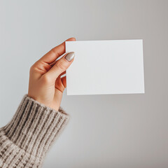 a woman hand holding a blank white postcard ,against a minimal background 