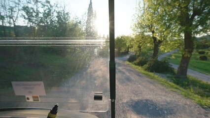 Golf cart driving along the road of golf course, sunshine through the windscreen while driving, transport for delivering players to golf course