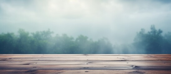 A wooden table set against a foggy forest backdrop with tall trees, green grass, and cumulus clouds in the sky, creating a serene natural landscape