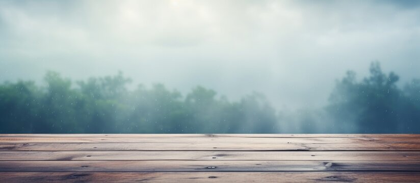 A wooden table set against a foggy forest backdrop with tall trees, green grass, and cumulus clouds in the sky, creating a serene natural landscape