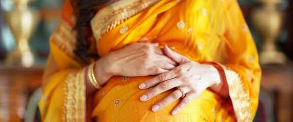 A close-up of a glowing Indian woman her hands tenderly caressing her belly - obrazy, fototapety, plakaty