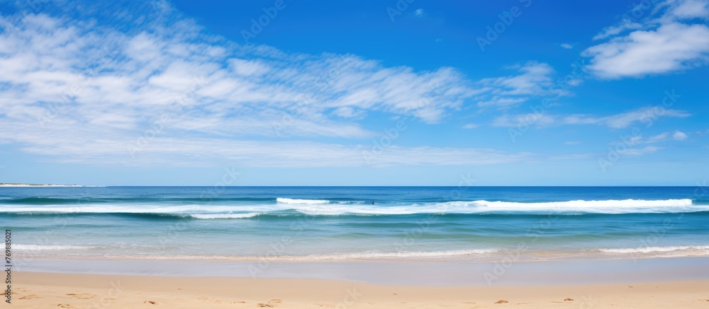 Aufkleber a hazy image of a beach with gentle waves rolling in under a sunny sky, creating a tranquil scene of