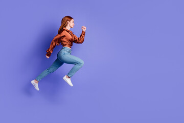 Full length profile portrait of nice young woman jump run empty space wear brown shirt isolated on purple color background - obrazy, fototapety, plakaty