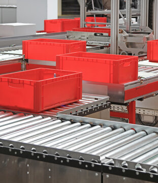 Red Plastic Crates at Conveyor Rollers in Automated Distribution Warehouse
