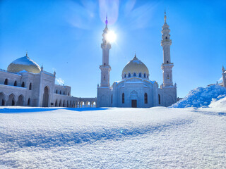 Golden-domed mosque with twin minarets against a clear blue sky. Sunlight Glistening on White...