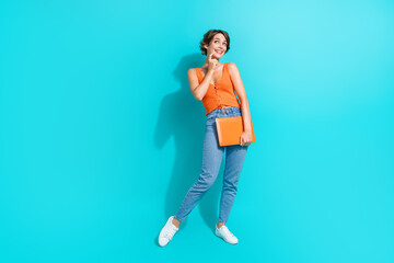 Full length photo of minded woman wear orange singlet jeans hold laptop look at promo empty space isolated on turquoise color background