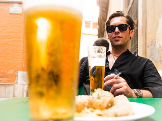 man in his thirties with sunglasses beer and cigar on the terrace of the bar - 769898448