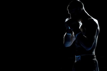 silhouette Angry MMA man fighter stand wearing boxing gloves on a black background