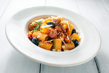 Piatto di deliziosi rigatoni conditi con sugo di salsiccia e olive nere, pasta italiana, cibo...