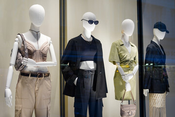 four mannequins in stylish clothes shop window