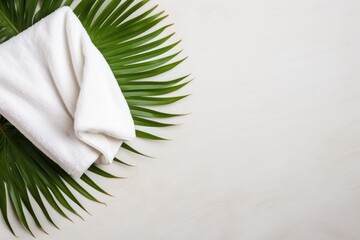 Spa concept - top view of a white towel on a green palm leaf. Copy space