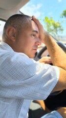 Adult man, sitting in the car, holding his head with one hand, with a sad face and a lost look. Receiving bad news. Personal problems.  Health problems.  Sudden migraine.  Economic crisis.