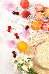 Summer fashion banner on a bright background. Straw hat, fruits and berries in an eco-bag and chamomile flowers on a sunny table. Vacation and travel concept, outdoor camping and holiday party,