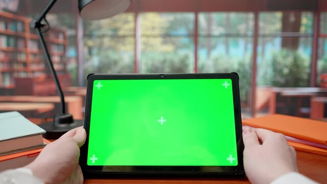 Tablet with Green Screen on Library Desk. Advertising area, workspace mock up.