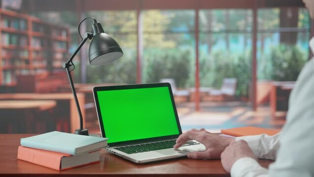 A laptop with a green screen chroma key on the library table. Advertising area, workspace mock up.