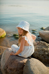 young girl seating on the rocks at the beach 
