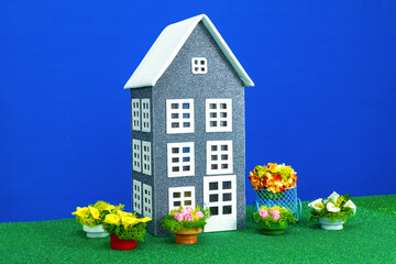 One gray house with flowers around on a green surface