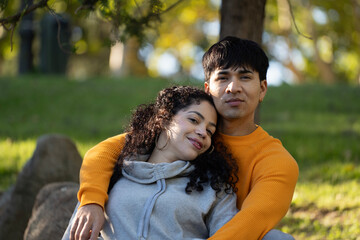 Happy hispanic couple relaxing and hugging in a park