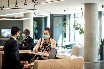 Diverse business people at hotel reception desk with face masks
