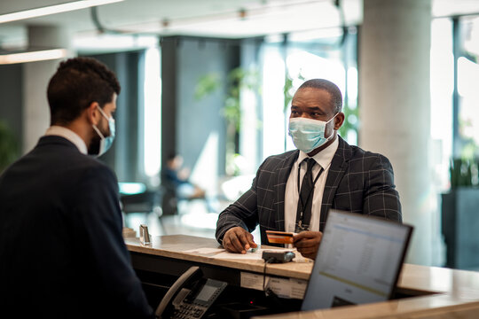 Businessman checking in hotel at reception during pandemic