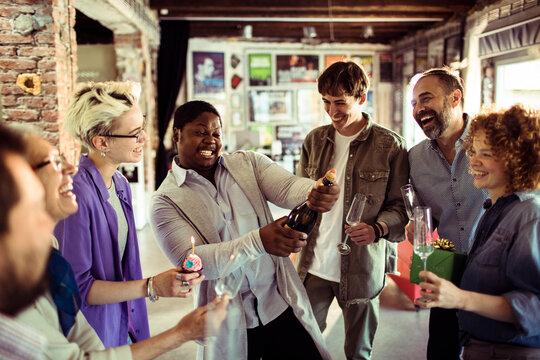 Multigenerational and diverse group of people celebrating a birthday in a startup company office