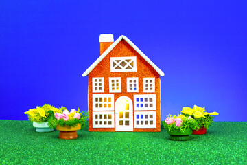 One low orange house with flowers around on a blue background