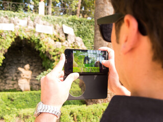 man taking photos with his cell phone in carmen de los martires park in granada spain - 769927435