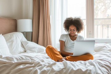 Obraz premium A woman is sitting on a bed with a laptop open in front of her