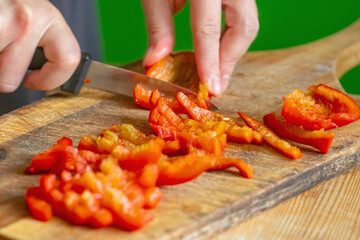 Italian bread and ingredients - parmesan, olive oil, tomato, spice and herbs. Chef's hands cuts red pepper slices on a pizza. Horizontal image.