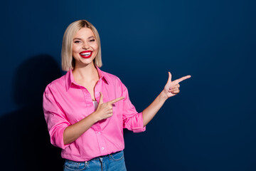 Photo of positive girl with bob hairstyle dressed pink shirt indicating at promo empty space...