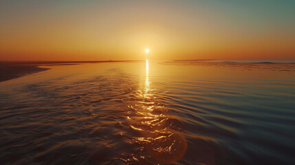 Naklejka premium A breathtaking sunrise over a tranquil river, casting a golden glow on the calm waters, with the ocean in the distance under a clear, morning sky.
