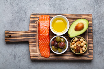 Food sources of healthy unsaturated fat: fresh raw salmon fillet, avocado, olives, nuts on cutting board on rustic stone background top view. Omega 3 and oil products, healthy nutrition and keto diet - 769945095
