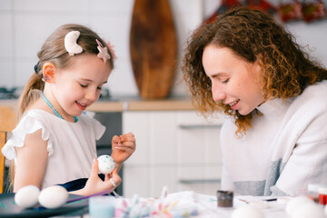 Mother and her daughter painting eggs. Family celebrating Easter. preparing for Easter at home