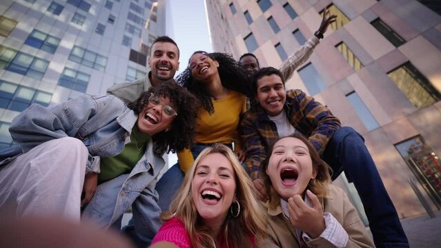 A group of happy people is sharing a fun moment. Young friends take a selfie picture during a leisure event. The team is traveling together. Smiling community portrait looking at camera