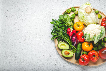 Rustic wooden tray with selection of fresh vegetables and greenery on white kitchen table top view. Vegetarian or diet food from organic ingredients, healthy nutrition concept, space for text - 769951673